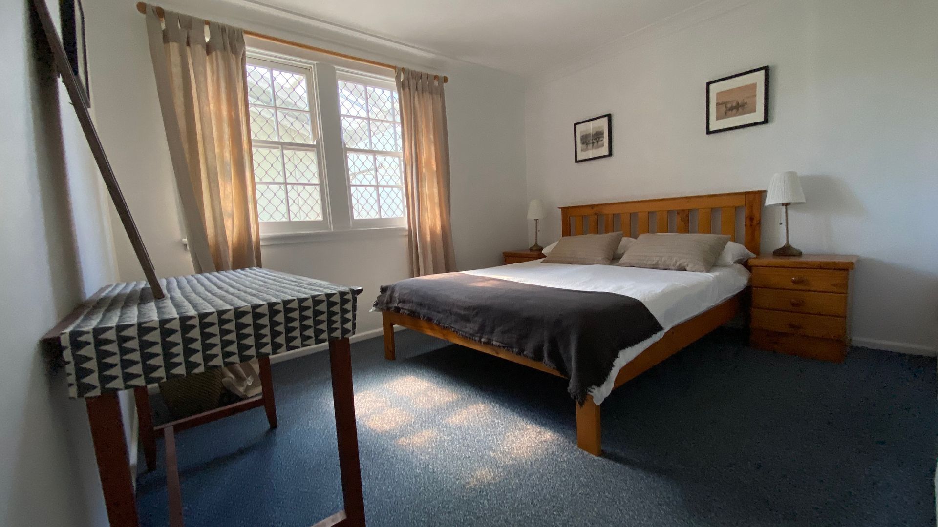A bedroom with a bed, a chair, a nightstand, and a window with curtains.