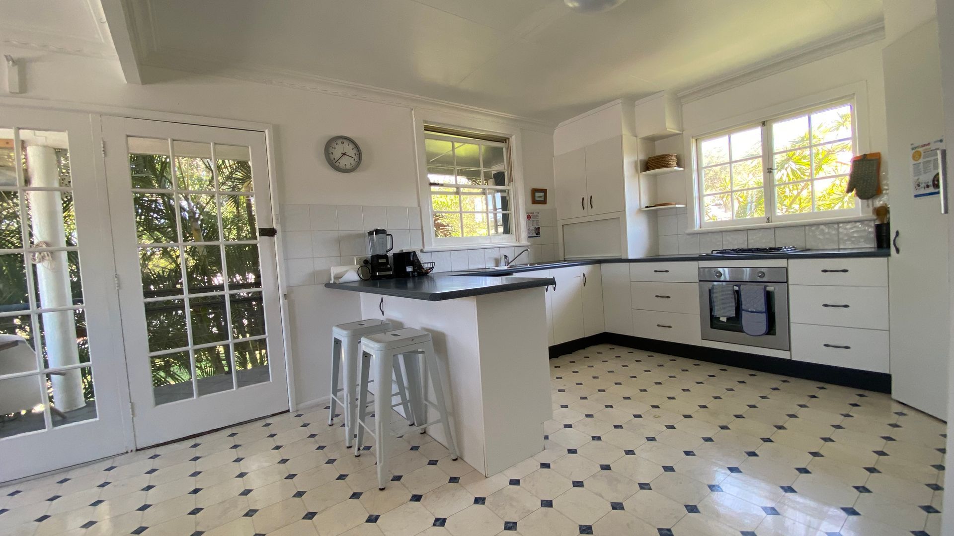 A kitchen with a central island, white cabinets, a stove, and a clock on the wall.