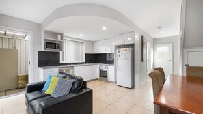 A compact kitchen with white cabinets, a microwave, a refrigerator, and a stove. - Adrift, 5B Scott Street (Crescent Head)