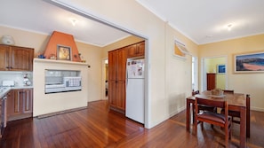 A kitchen with wooden cabinets, a white refrigerator, and a dining area with a wooden table and chairs.