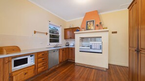 A kitchen with wooden cabinets, a built-in oven, and a microwave. - Berry, 16 East Street (Crescent Head)