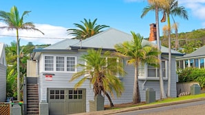 A two-story house with a garage, a chimney, and a sign indicating holiday letting. - Berry, 16 East Street (Crescent Head)