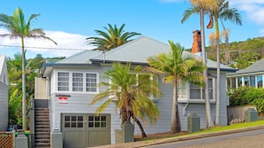 A two-story house with a garage, a chimney, and a sign indicating holiday letting. - Berry, 16 East Street (Crescent Head)