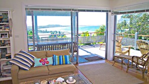 Ein Zimmer mit einer Couch, einem Couchtisch und Blick auf eine Terrasse mit Gartenmöbeln.