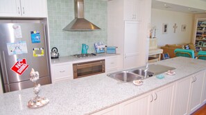 A kitchen with a stainless steel refrigerator, a stove, a sink, and a dishwasher.