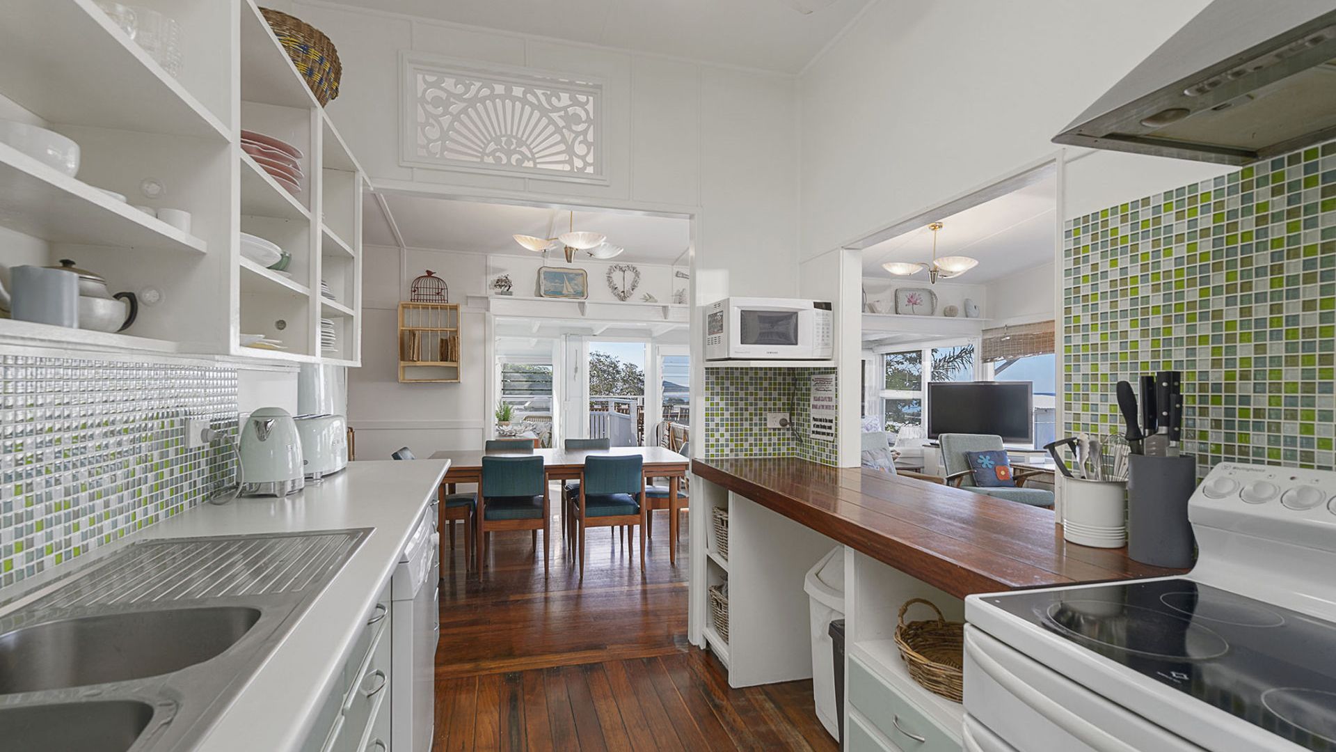 A kitchen with white cabinetry, a wooden dining table with chairs, a microwave, and a stove.