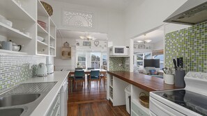 A kitchen with white cabinetry, a wooden dining table with chairs, a microwave, and a stove.
