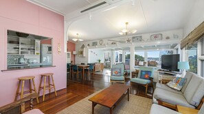 A spacious living area with a kitchen, dining space, and seating area, featuring a large window and a television.