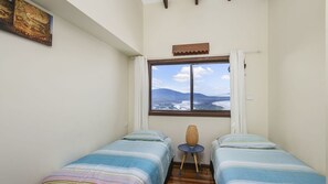Een kleine kamer met twee bedden, een raam met uitzicht op een landschap en één stoel.