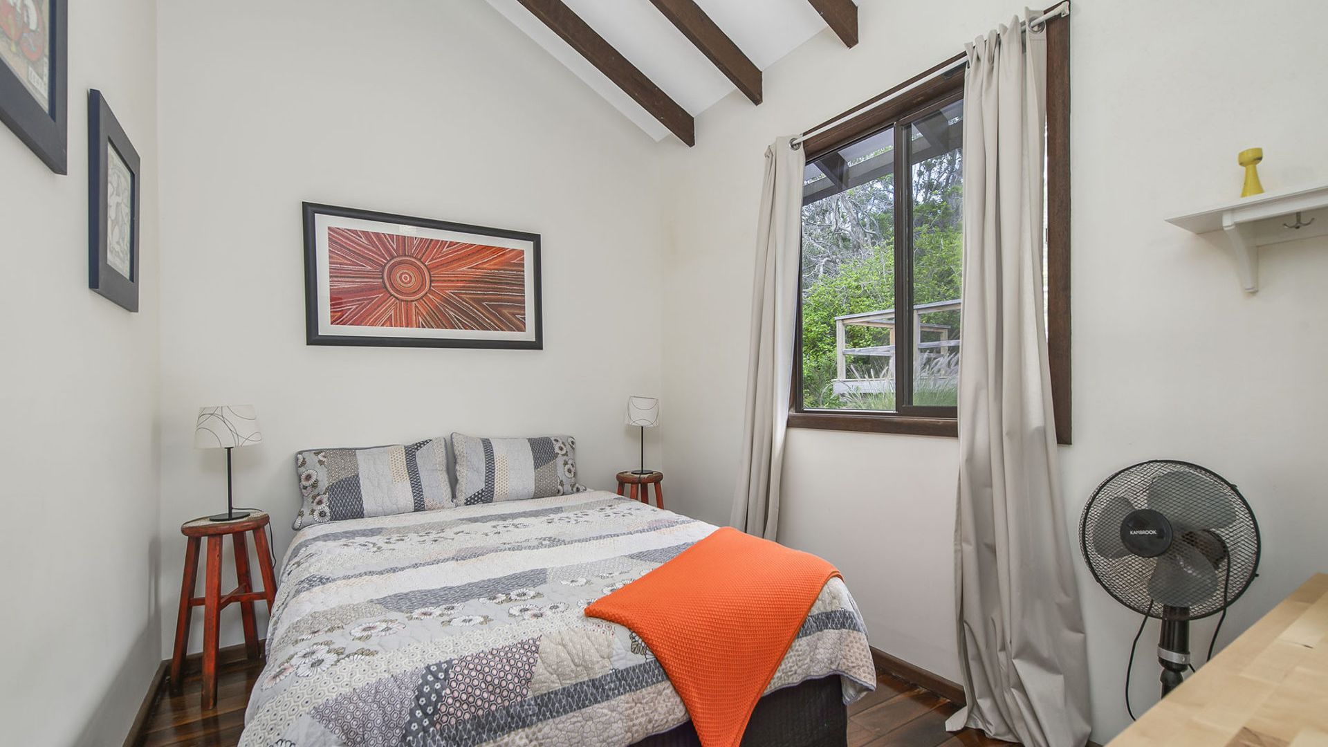 Un dormitorio con cama, ventana, ventilador y un cuadro en la pared.