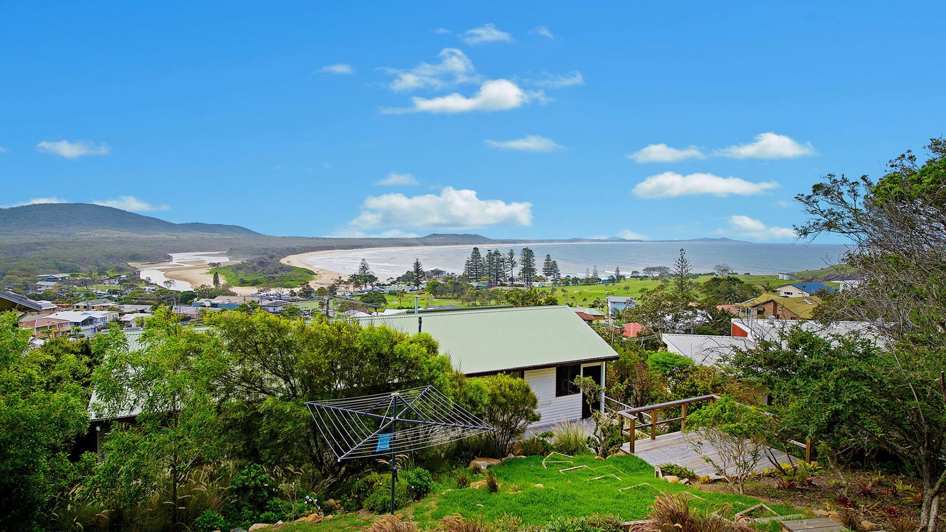 A coastal town with a beach, houses, and greenery.