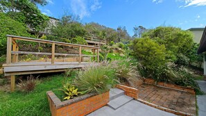 A wooden bridge over a garden with brick planters and a variety of plants.