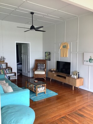 Cozy living area with a sofa, chair, and TV on a wooden stand, surrounded by a book collection.
