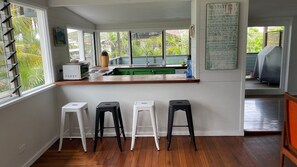 A kitchen with a wooden countertop, a sink, and three stools.