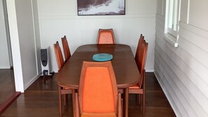 A dining area with a wooden table and matching chairs, a blue placemat, and a kitchen appliance to the left. - Good Vibes, 18 East Street (Crescent Head)
