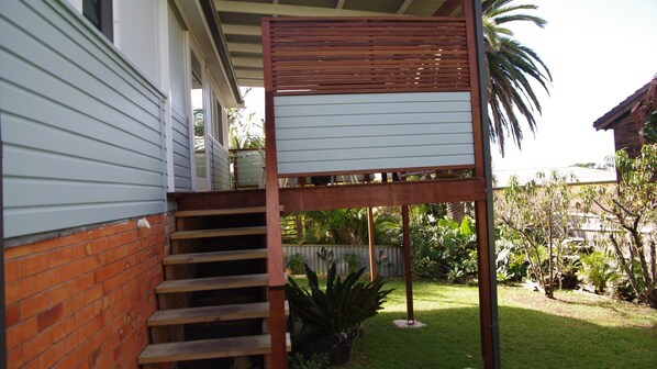 A wooden staircase leading to a covered porch with a metal railing.