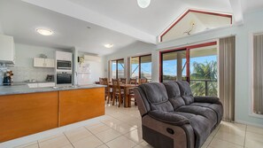 A modern kitchen with built-in appliances, a dining area with wooden furniture, and a large window with a view of the outdoors.