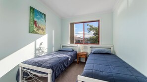 Una habitación con dos camas individuales, un ventanal con vistas y un cuadro en la pared.