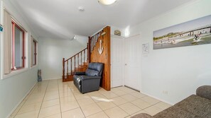 Un salón amplio con una escalera, un sofá de cuero y una decoración de temática playera.