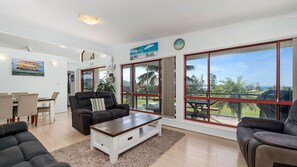 A spacious living room with a large window, a dining area, and a view of the outdoors.