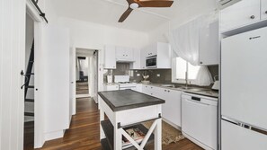 A kitchen with white cabinetry, a central island, and a ceiling fan.