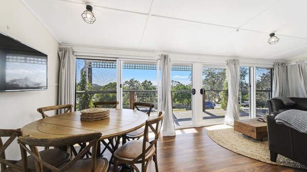 A spacious room with a dining area, a sofa, and a view of the outdoors.