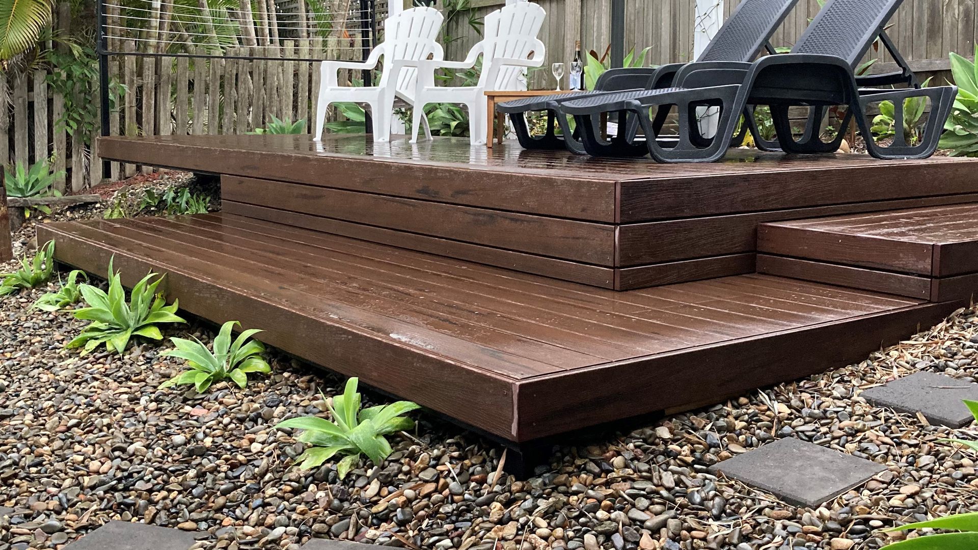 A wooden deck with steps leading to a seating area with chairs.