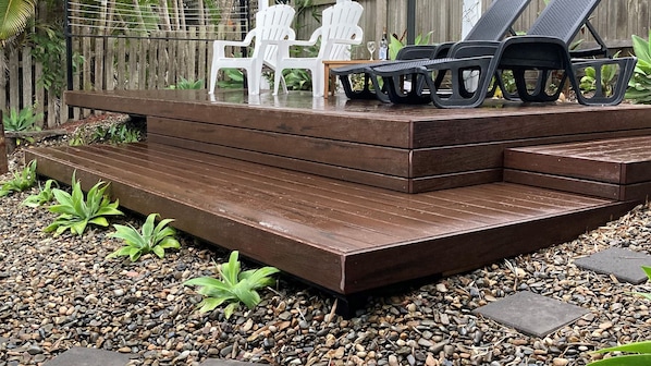 A wooden deck with steps leading to a seating area with chairs.