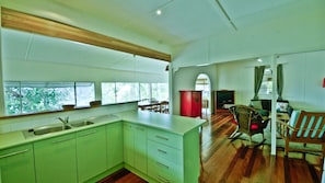 A spacious kitchen with a large island, wooden flooring, and a dining area with a television and seating.
