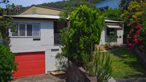 A residential house with a red garage door, a small porch, and a well-maintained lawn.