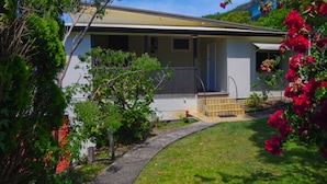 A single-story house with a front porch, a small garden, and a pathway leading to the entrance. - Rosemaree, 24 East Street (Crescent Head)