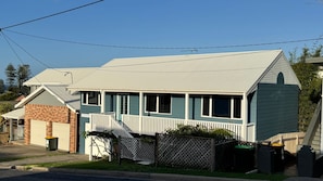 A two-story house with a front porch, a brick section on the left, and a fenced yard.