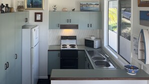 A compact kitchen with a refrigerator, stove, microwave, and sink.