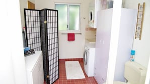 A compact laundry room with a washing machine, a drying rack, and a folding area. - Bellevue Holiday House Crescent Head (Crescent Head)