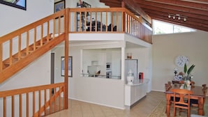 A two-story home with a wooden staircase, a kitchen with modern appliances, and a dining area with a table and chairs. - Bellevue Holiday House Crescent Head (Crescent Head)