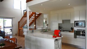 A modern kitchen with white cabinets, a central island, a microwave, and a stove.