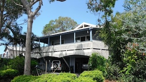 A two-story house with a balcony, surrounded by lush greenery. - Bellevue Holiday House Crescent Head (Crescent Head)