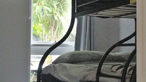 A bunk bed with a window view of greenery.