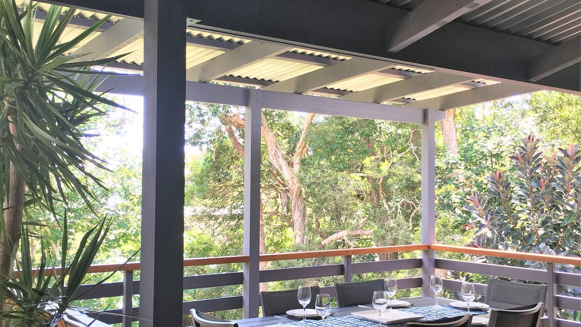 An outdoor seating area with tables and chairs, surrounded by greenery.