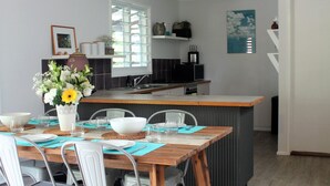 Una cocina moderna con comedor, que incluye una mesa de madera, sillas y un jarrón con flores.
