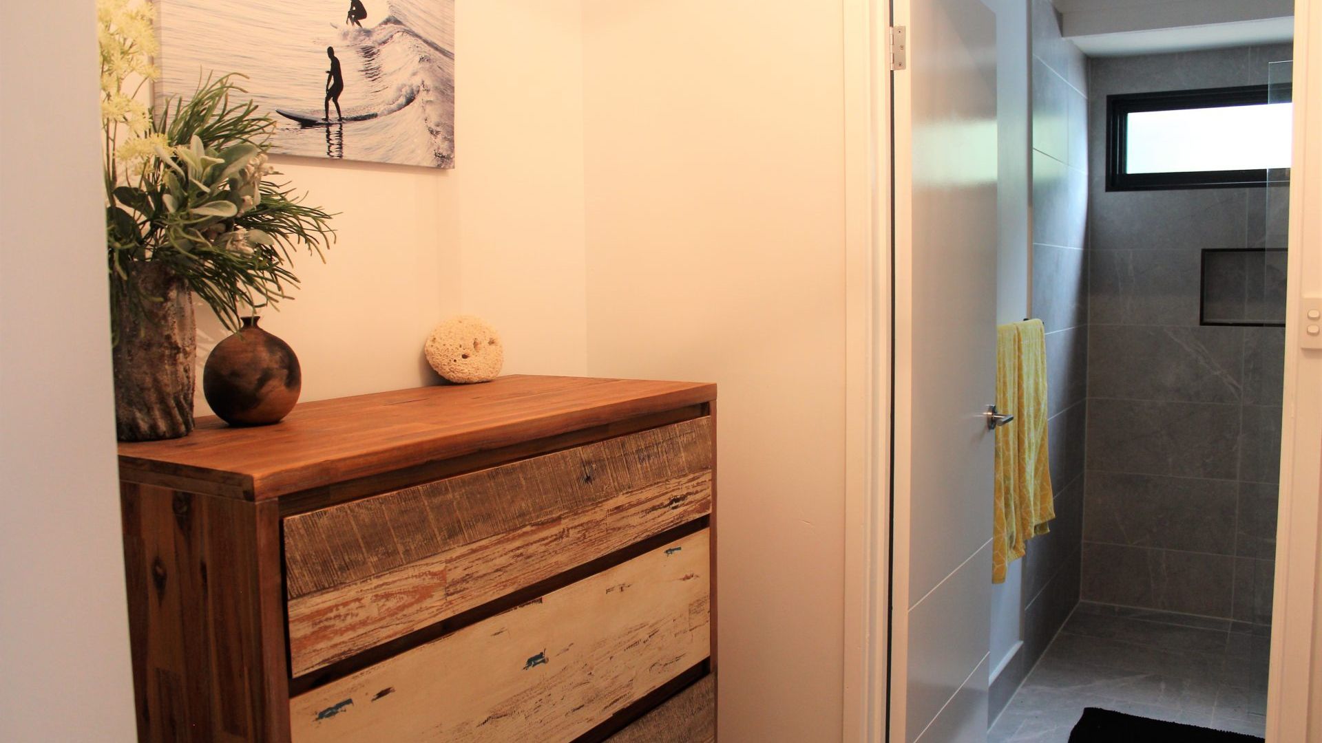 A bathroom with a wooden vanity, a towel rack, and a shower area.