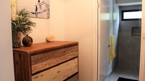 Un baño con tocador de madera, perchero y zona de ducha.