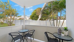 Un balcon avec deux tables et des chaises, une statue de Bouddha et une plante en pot.