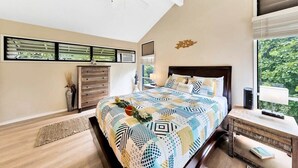 Un dormitorio con cama, mesita de noche, cómoda, ventilador de techo y ventana con persianas.