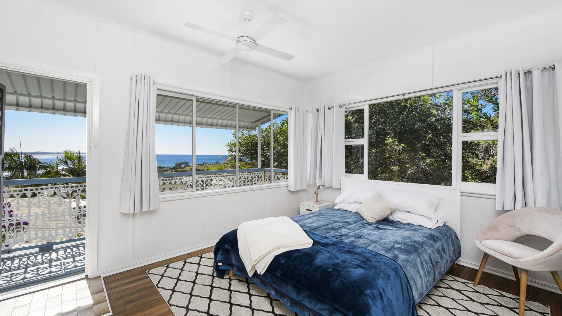 A bedroom with a bed, a chair, and a view of the ocean.