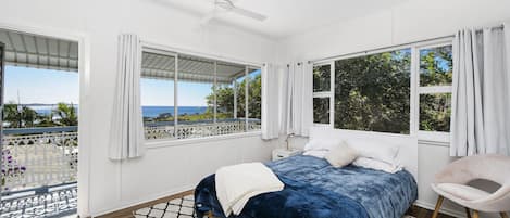 Ein Schlafzimmer mit einem Bett, einem Sessel und Meerblick.