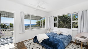 Un dormitorio con cama, una silla y vista al océano.
