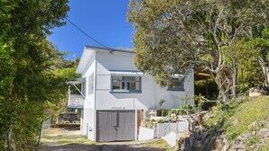 Une maison à deux étages avec un garage, une véranda et un jardin.
