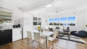 Una cocina moderna con lavavajillas, cafetera y comedor con mesa y sillas.