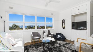 A room with a large window, a television, a sofa, a chair, and a small table.